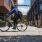 Photograph of person on biking crossing the pedestrian street, Pearl Street, featuring restaurants and outdoor dining.