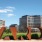 The Ilume apartment complex as seen from outside, including abstract metal sculptures and a grassy field.